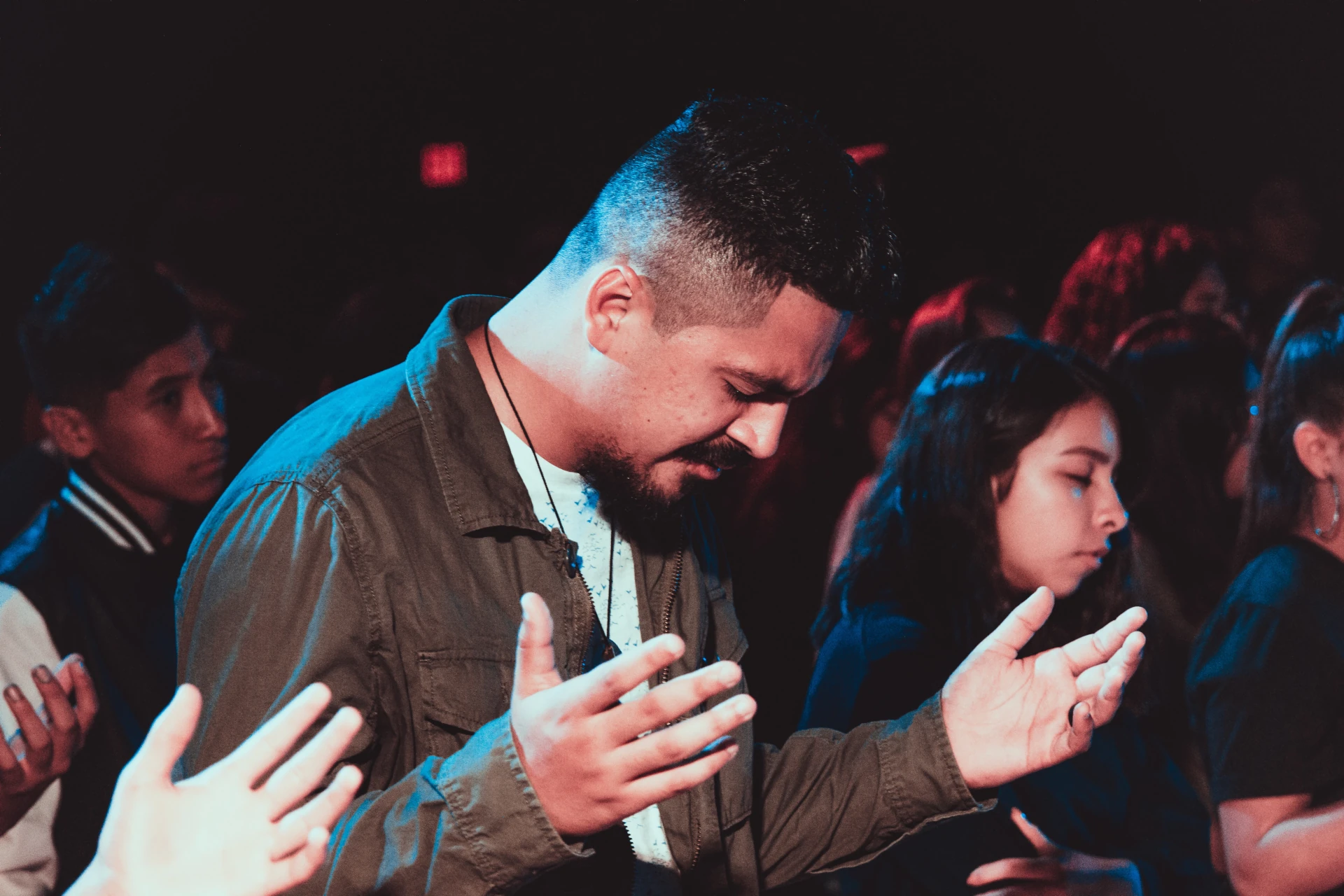 A man and woman praying in front of other people.