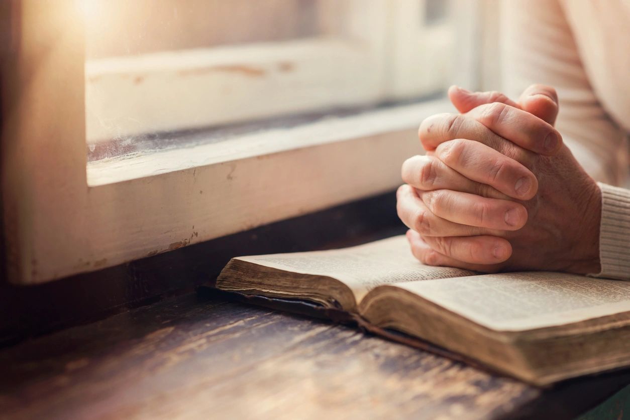 A person is praying on top of an open book.